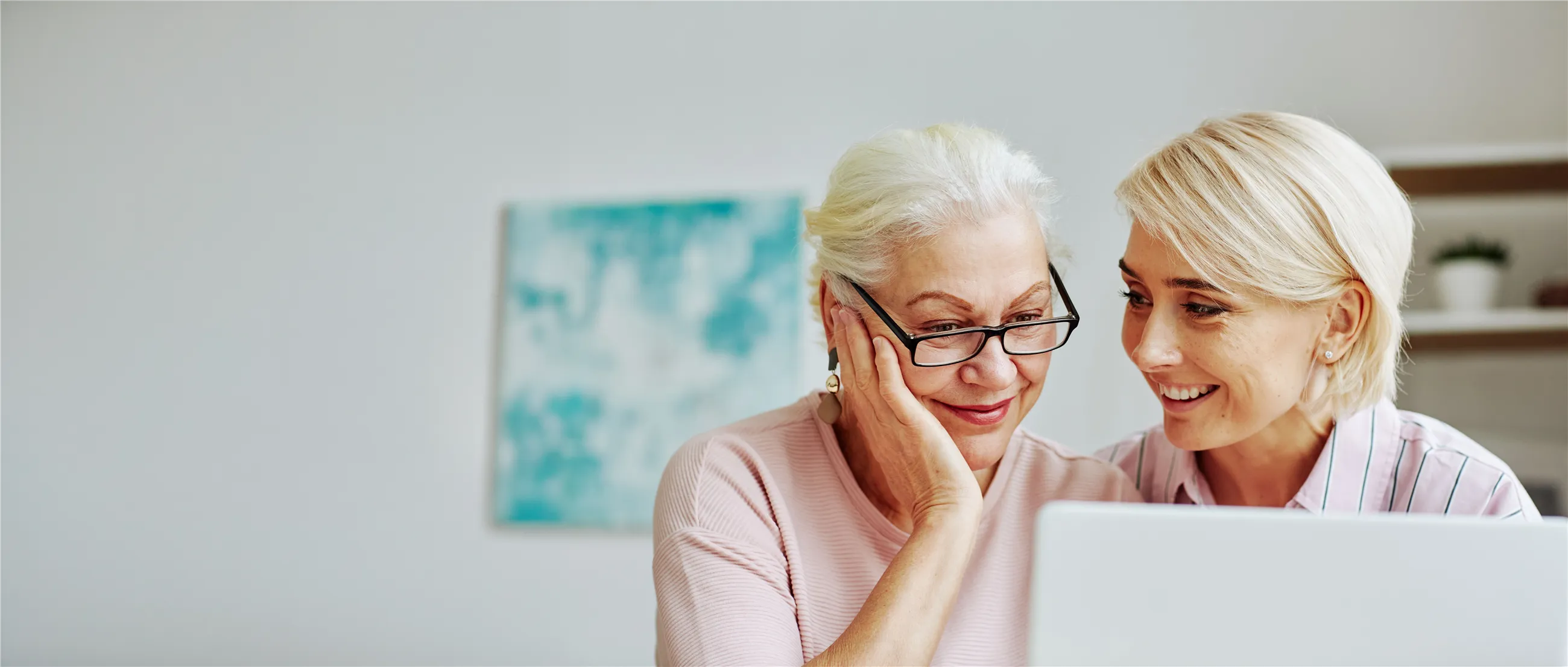 Tochter und Mutter schauen gemeinsam lächelnd auf einen Laptop